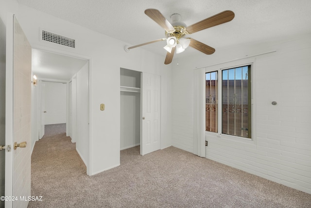 unfurnished bedroom with light carpet, a textured ceiling, a closet, and ceiling fan