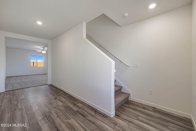 staircase with ceiling fan and wood-type flooring