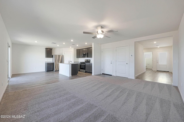 unfurnished living room with ceiling fan, light hardwood / wood-style floors, and sink