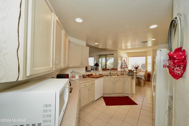 kitchen with sink, white appliances, kitchen peninsula, and light tile patterned flooring