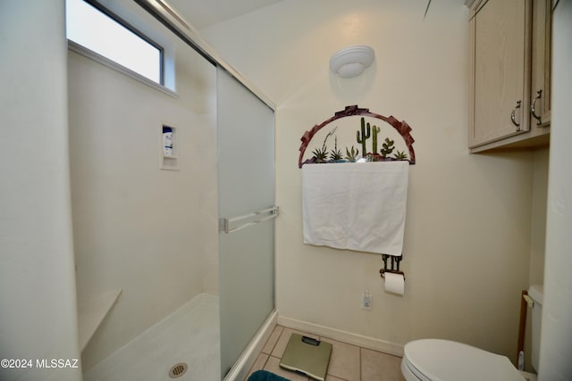 bathroom featuring tile patterned flooring, a shower with shower door, and toilet