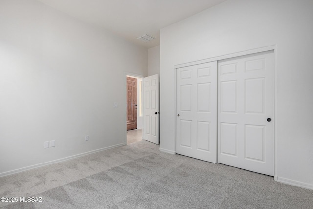 unfurnished bedroom with light carpet and a closet