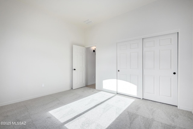 unfurnished bedroom featuring light colored carpet and a closet