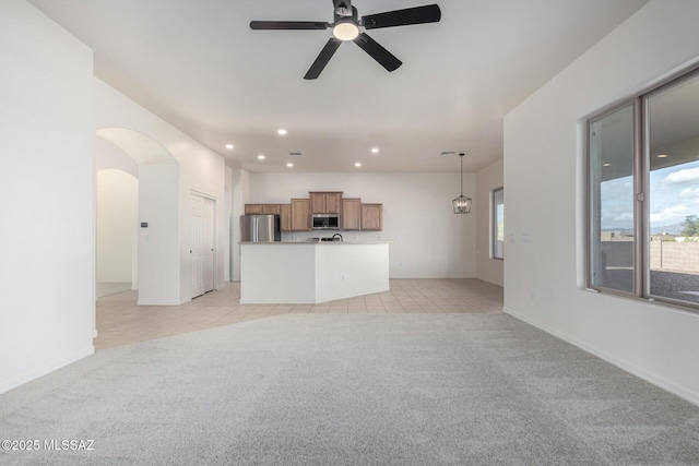 unfurnished living room featuring light colored carpet and ceiling fan