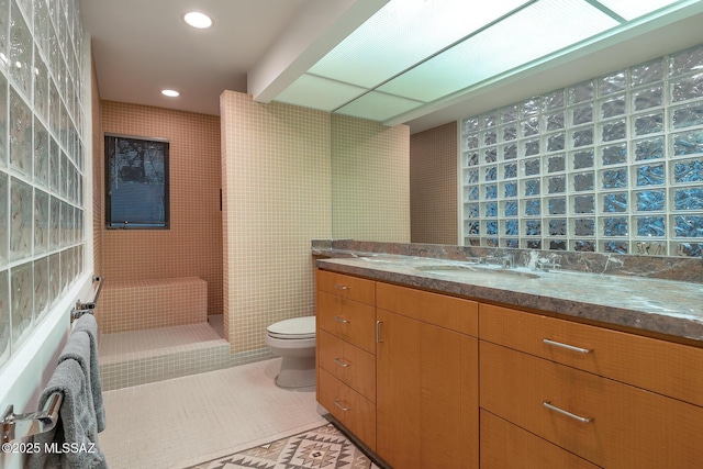 bathroom featuring toilet, tile patterned flooring, tile walls, and vanity