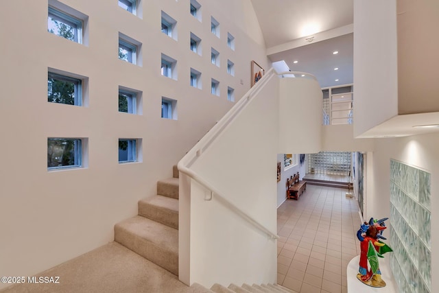 stairway with a towering ceiling and tile patterned flooring