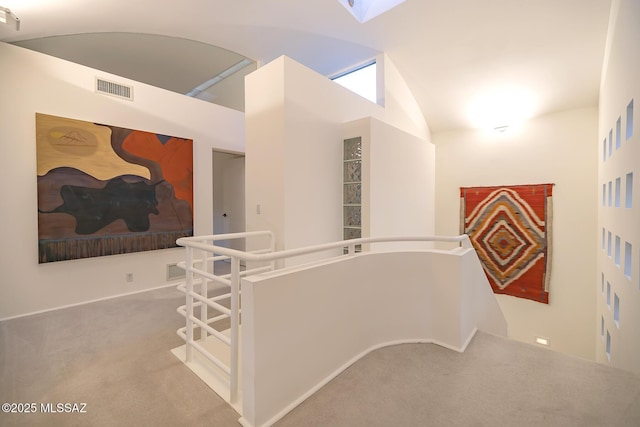 hall with high vaulted ceiling and light colored carpet