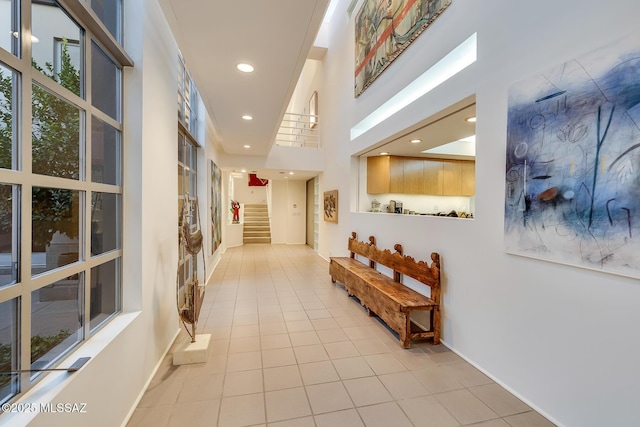 hallway with light tile patterned floors and a towering ceiling