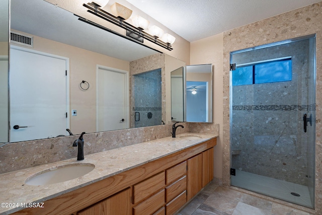 bathroom with vanity, an enclosed shower, and a textured ceiling