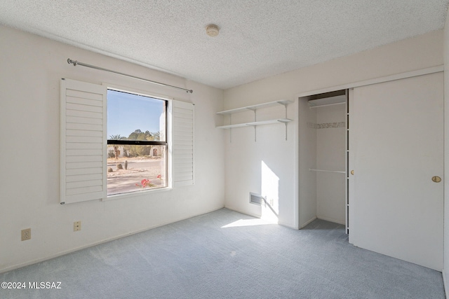 unfurnished bedroom with a textured ceiling, light colored carpet, and a closet