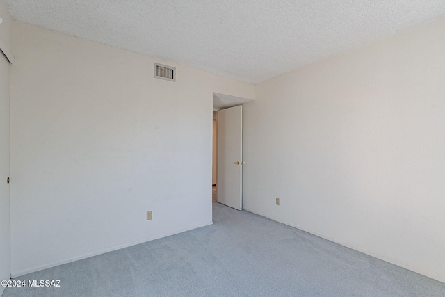 unfurnished room featuring light carpet and a textured ceiling