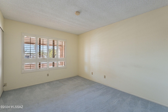 unfurnished room featuring light carpet and a textured ceiling