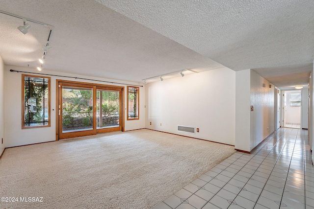 unfurnished living room with a textured ceiling, light tile patterned flooring, and rail lighting