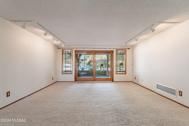 carpeted spare room featuring rail lighting and a textured ceiling