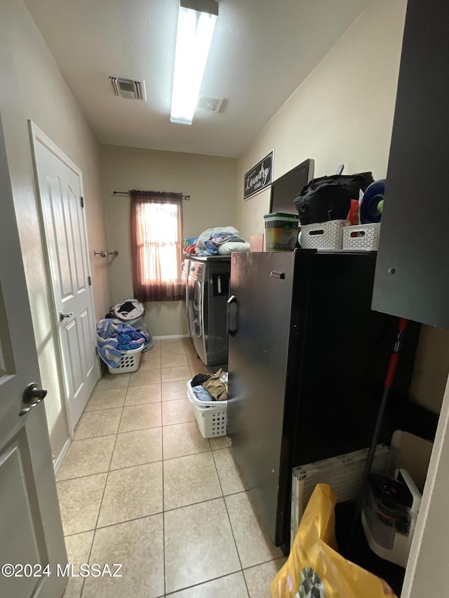 washroom with cabinets, light tile patterned floors, and washing machine and clothes dryer