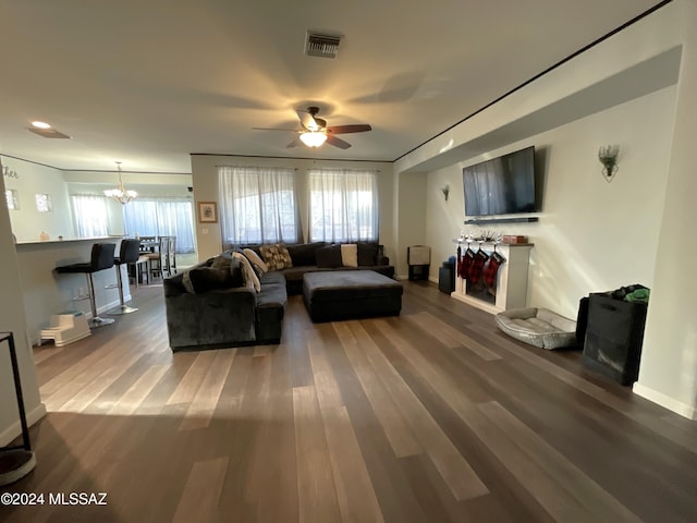 living room with ceiling fan with notable chandelier and hardwood / wood-style flooring