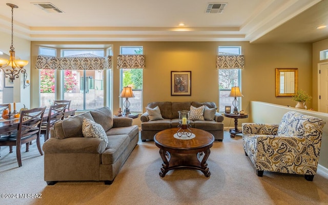 living room with carpet flooring, a chandelier, and a tray ceiling