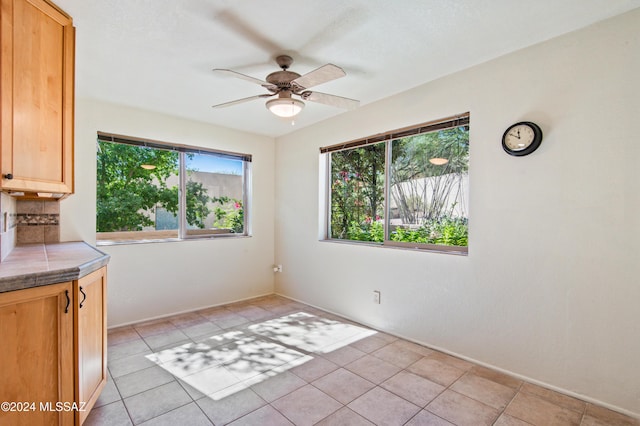 unfurnished dining area with ceiling fan and light tile patterned floors