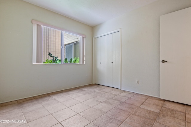 unfurnished bedroom featuring light tile patterned floors and a closet