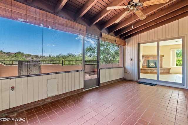 unfurnished sunroom featuring vaulted ceiling with beams, ceiling fan, and wood ceiling