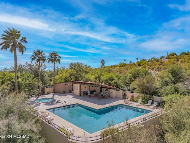 view of swimming pool featuring a hot tub and a patio area