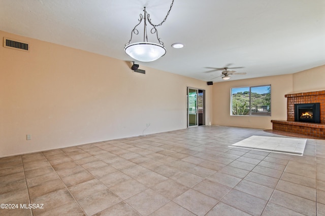 unfurnished living room featuring ceiling fan, a fireplace, and light tile patterned flooring