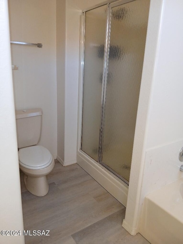 bathroom with toilet, wood-type flooring, and plus walk in shower