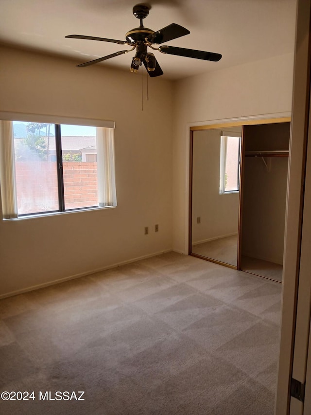 unfurnished bedroom featuring ceiling fan, light colored carpet, and a closet