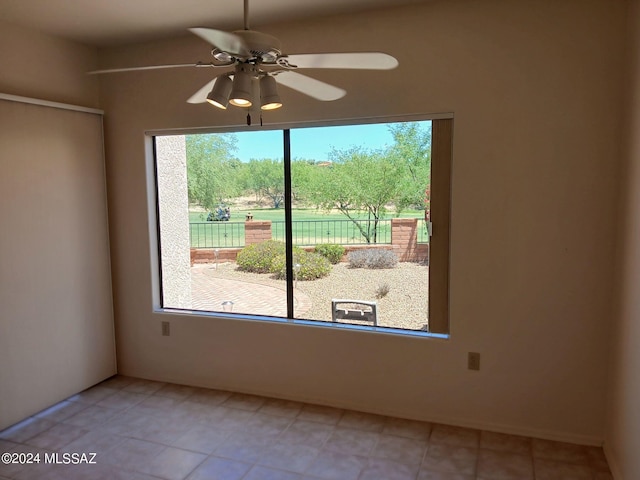 tiled spare room with a wealth of natural light and ceiling fan