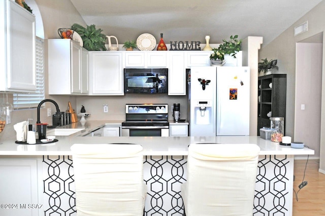 kitchen with white cabinetry, sink, white refrigerator with ice dispenser, and stainless steel range with electric cooktop