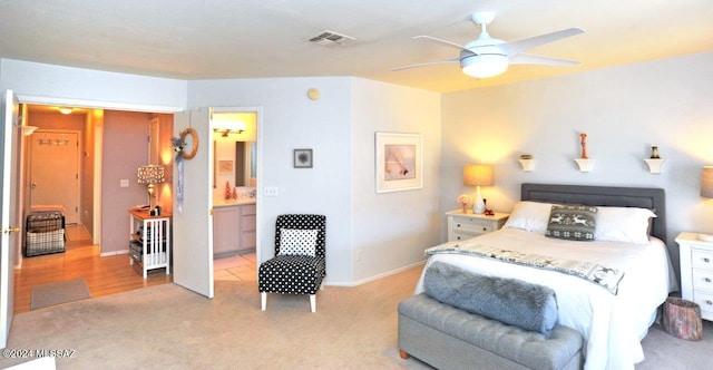 bedroom with connected bathroom, light colored carpet, and ceiling fan