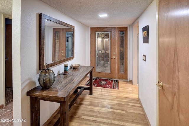 doorway to outside featuring a textured ceiling and light hardwood / wood-style flooring