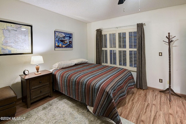 bedroom with ceiling fan, a textured ceiling, and light wood-type flooring