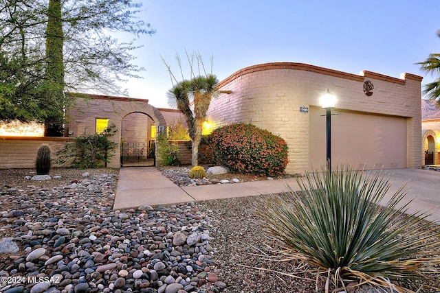 view of front facade with concrete driveway, a gate, fence, and an attached garage