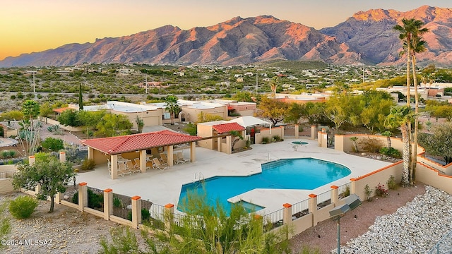 pool at dusk featuring a mountain view and a patio