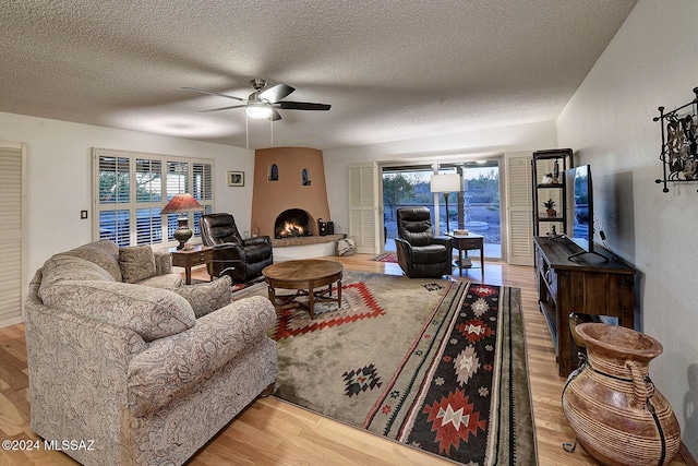 living room featuring wood-type flooring, a large fireplace, and ceiling fan