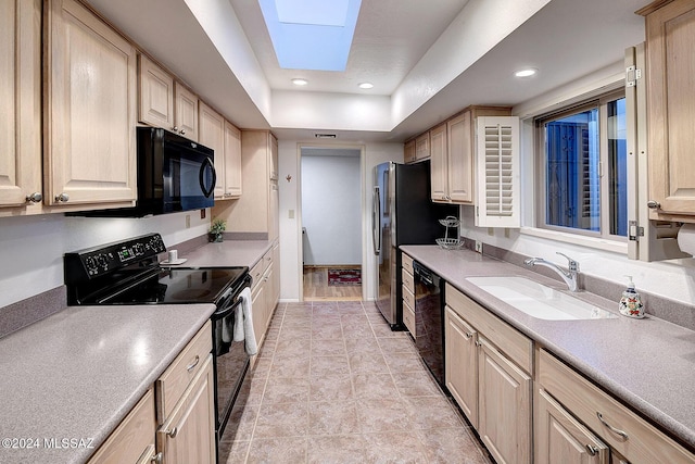 kitchen featuring light brown cabinetry, sink, a skylight, a tray ceiling, and black appliances