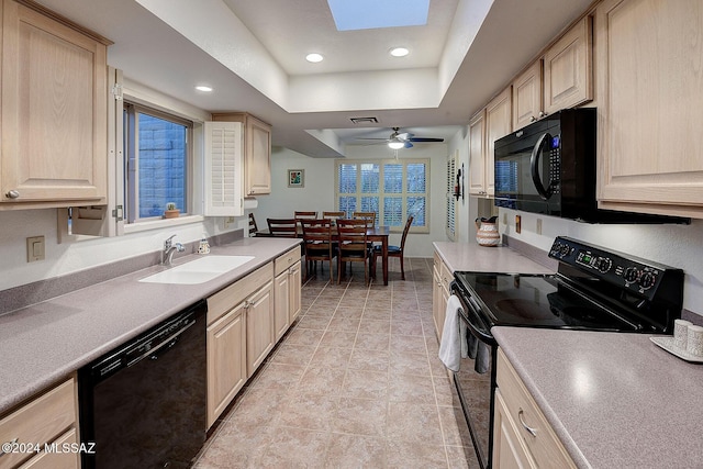 kitchen featuring sink, a skylight, black appliances, light brown cabinetry, and a raised ceiling