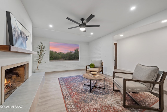 sitting room featuring a fireplace, light wood-type flooring, and ceiling fan