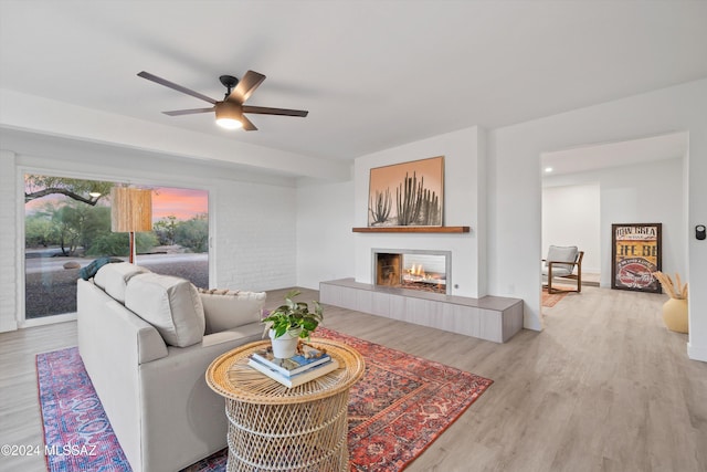 living room with hardwood / wood-style floors, ceiling fan, and a tiled fireplace