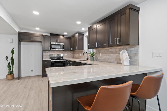 kitchen featuring light hardwood / wood-style floors, kitchen peninsula, and appliances with stainless steel finishes