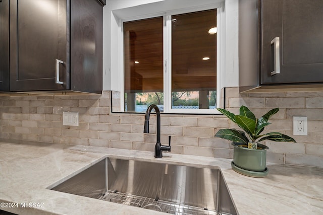 kitchen with decorative backsplash, dark brown cabinets, and sink