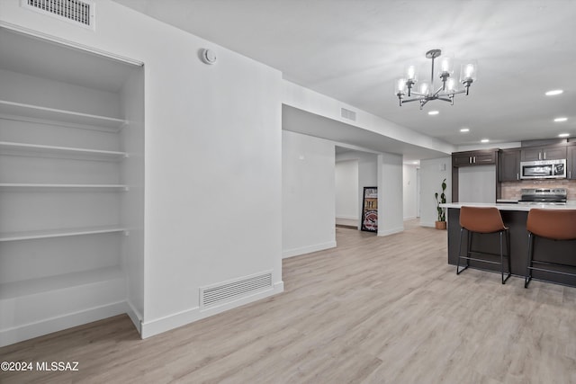 kitchen featuring appliances with stainless steel finishes, light hardwood / wood-style flooring, dark brown cabinets, and a breakfast bar area