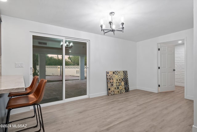 unfurnished dining area featuring light wood-type flooring and a notable chandelier