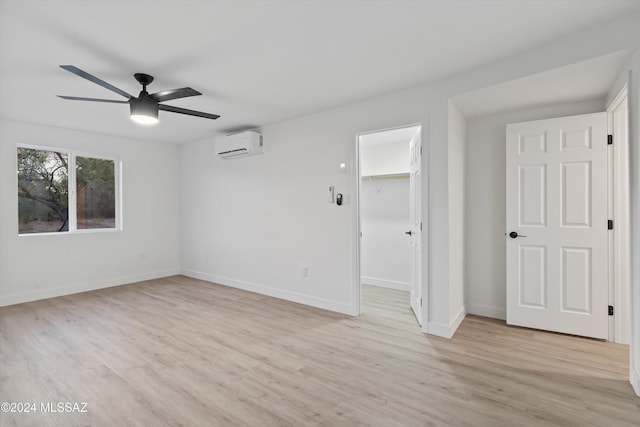 empty room with a wall unit AC, ceiling fan, and light hardwood / wood-style flooring