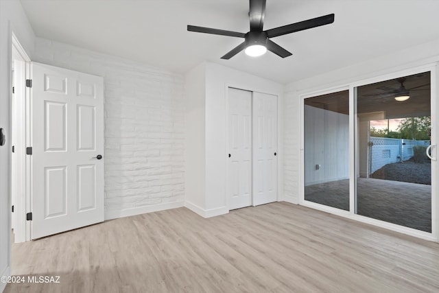 unfurnished bedroom featuring brick wall, access to outside, ceiling fan, light hardwood / wood-style floors, and a closet