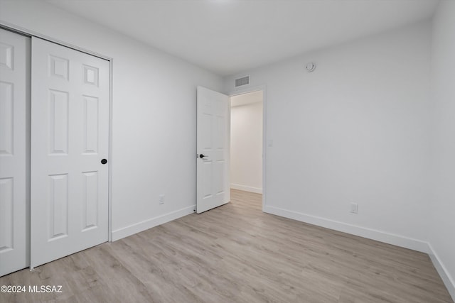 unfurnished bedroom with light wood-type flooring and a closet