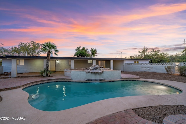 pool at dusk with a patio area