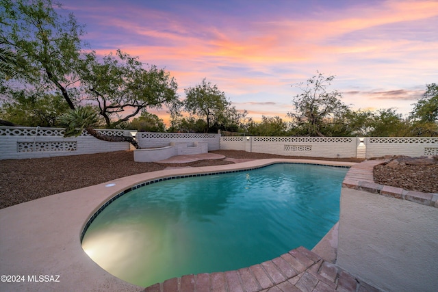 pool at dusk with a patio area