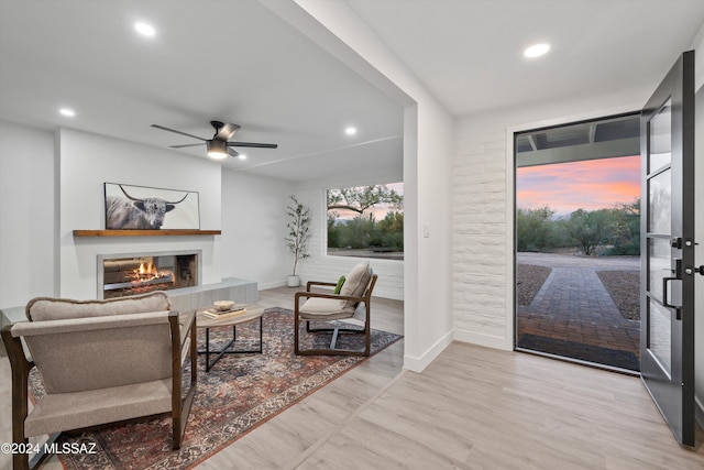 interior space featuring a tile fireplace, light hardwood / wood-style floors, and ceiling fan